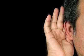 Human hand placed up against an ear