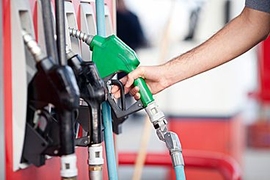 Photo of a hand holding a green gas handle at a gas station