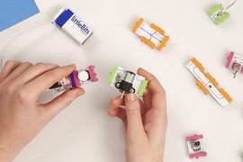 An example of the Bits modules. Here, a power source (blue) connects to a button (pink) that will trigger a motor (green). The orange modules to the side are extending wires.