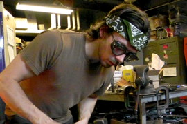 Man hammers a red-hot piece of molten glass