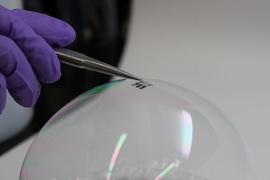 The MIT team has achieved the thinnest and lightest complete solar cells ever made, they say. To demonstrate just how thin and lightweight the cells are, the researchers draped a working cell on top of a soap bubble, without popping the bubble. 