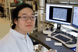Summer Scholar Justin Cheng holds an experimental sample of nanostructured gold on silicon that has potential for use in sensors and display technologies based on its selective light absorption properties.