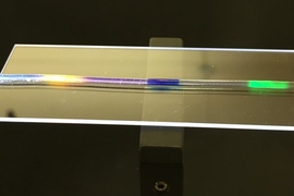 MIT researchers have developed a stretchy optical fiber in which they have injected multiple organic dyes (yellow, blue, and green regions). In addition to lighting up, the dyes act as a strain sensor, enabling researchers to quantify where and by how much a fiber has been stretched.