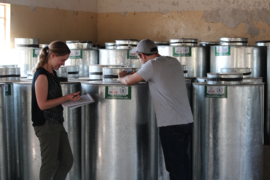 MIT students and CITE research assistants Emily Gooding and Mark Brennan examine a metal post-harvest storage silo as part of a study with the World Food Program in Uganda.