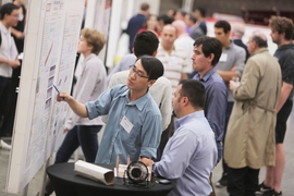 Lup Wai Chew (left) explains his research in Wind Enhancement in Urban Areas to alum Luis De Jesus.