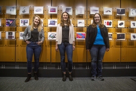 Left to right: Ann McInroy ’18, Isabella Didio ’16, and Jacklyn Herbst ’10, MEngM ’11 stand in front of a wall showing the history of Microsoft’s hardware since the 1980s in Building 88 of Microsoft’s campus located in Redmond, Washington.