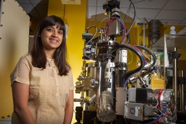 Postdoc Reshma Rao stands next to a pulsed laser deposition system, which is used to deposit well-defined thin films of catalyst materials. 