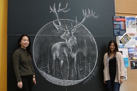 Jessica Xu and Priscilla Wong stand in front of their finished chalk art in the Stata Center.