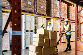 Three workers in a warehouse wearing protective face masks
