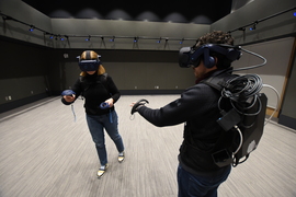 Photo of two people using untethered VR headsets and backpacks in the MIT.nano Immersion Lab