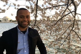 Thomas Searles standing by a cherry blossom and the Tidal Basin in Washington