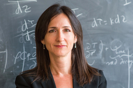 Photo of Sara Seager in front of a chalkboard covered in equations