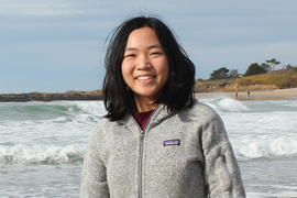 Headshot photo of Amy Jin standing on a beach and wearing a fleece jacket