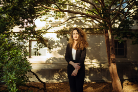 Photo of Maya Nasr standing in the shade of a tree on a sunny day