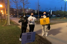 The MIT students outdoors at night, giving thumbs-up