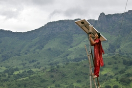 Barefoot woman on a ladder, adjusting a solar light