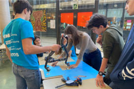 Photo of several students standing around a table with robot parts