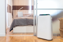 Photo of a standing portable air purifier in front of a bedroom