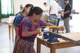 Photo of a Guatemalan woman using a hacksaw in a workshop.