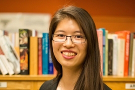 Headshot photo of Cathy Wu, who is standing in front of a bookcase.