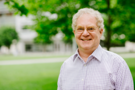 Portrait photo of Alan Grossman standing in Hockfield Court, with trees and a building in the background