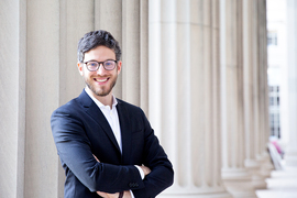 Photo of Francesco Benedetti with arms crossed, standing in front of columns.