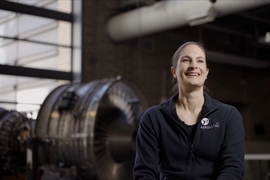 Photo of Andrea Henshall wearing an AeroAstro shirt and seated in a hangar