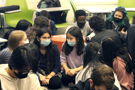 Photo of a dozen students talking in groups