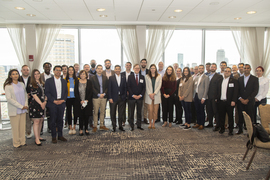 A large group of people in business attire posing in a semicircle.
