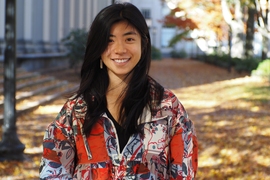 Portrait photo of Sarah Cen posing outdoors in a colorfully patterned jacket
