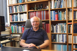 Harry L. Tuller sits in a chair in front of a bookcase in his office at MIT.