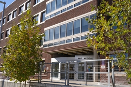 Photo of MIT Medical, a four-story brick building, with trees in front