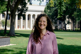Photo of Katya Boukin standing in MIT's Killian Court, a grassy area in front of the MIT Dome