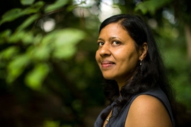 Portrait photo of Ila Fiete with green foliage in the background