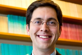 Headshot of Matthew Notowidigdo standing in front of a bookshelf