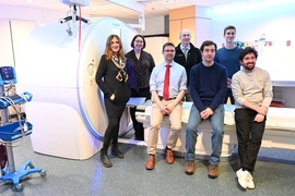 Photo of 7 researchers posing in front of a CT scanner.