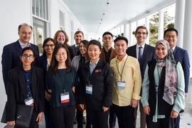 13 people in business attire pose for a group photo on a large, white covered porch
