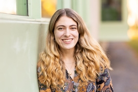 Aviva Intveld, leaning against a wall and smiling 