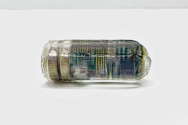 A tiny transparent pill with textured surface is on a table. You can barely see green computer chip inside.