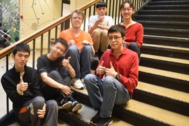 Six students sitting on a stairwell and giving thumbs-up.