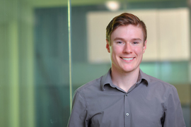 Portrait of Michael Howland standing in front of a glass wall