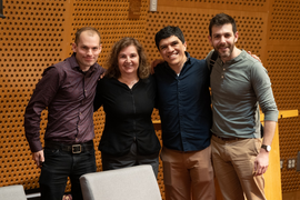 Phillip Isola, Daniela Rus, Armando Solar-Lezama, and Jacob Andreas pose arm-in-arm against an amber background