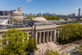 Aerial view of MIT campus building entrance with Boston skyline in the distance