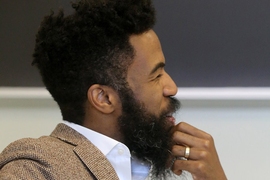 Closeup of Joshua Bennett, pictured in profile, seated in front of a blackboard