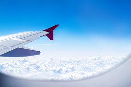 View from an airplane window showing a wingtip above fluffy, white clouds