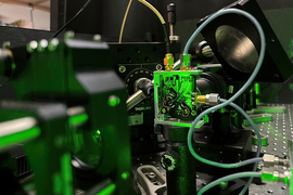research paper on quantum computing closeup of lab equipment under green light showing a rectangular sensor with cables