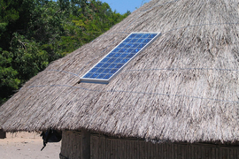 A single solar panel is installed on a thatched roof