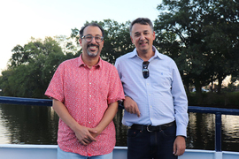 Youssef Marzouk and Nicolas Hadjiconstantinou pose with a body of water and trees in the background.