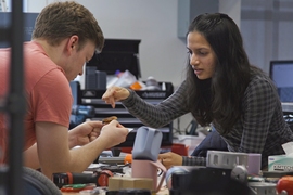 Sharmi Shah and Andrew SaLoutos hunch over a cluttered table, examining some small object