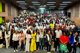Hundreds of participants of the national conference of women artisanal miners stand for a photo in an auditorium